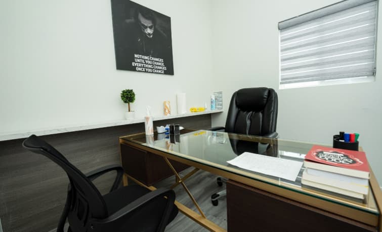 A Cozy Home Office With A Desk, Chair, And Framed Picture On The Wall