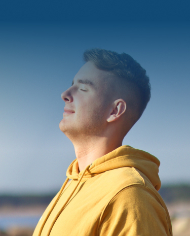 A Man Wearing A Yellow Hoodie Gazes Upward, Observing The Sky Above Him