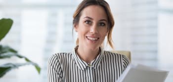 A Woman Beams With Happiness While Holding A Piece Of Paper