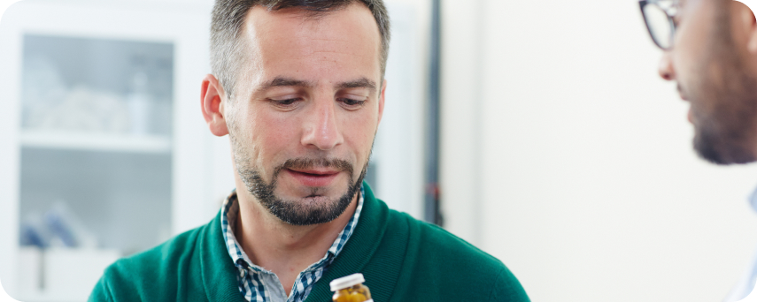 A Man Holds A Medicine Bottle Near His Face, Appearing Contemplative