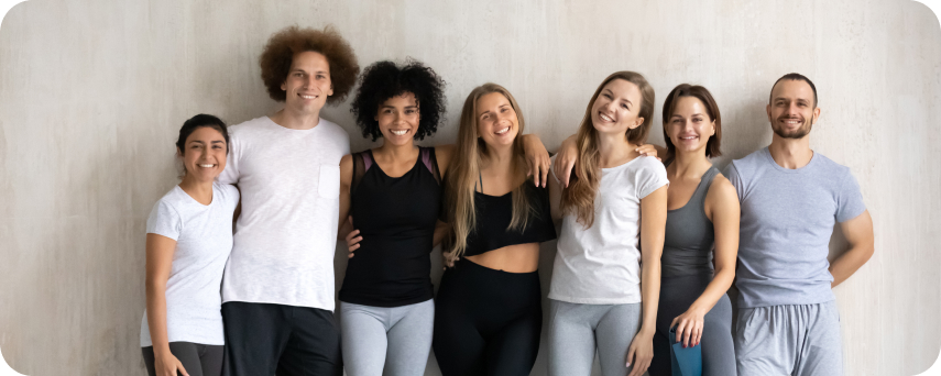 A Diverse Group Of Individuals Smiling Together In Front Of White Wall