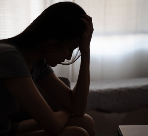 A Woman On A Couch, Head In Hands, Showing Stress Or Contemplation