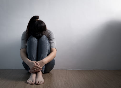 A Woman Sitting On The Floor With Her Hands Folded, Looking Serene In Calm Indoor Setting