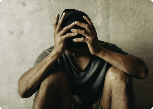 Man Seated On The Ground, Hands On His Head, Conveying Sense Of Worry Or Contemplation