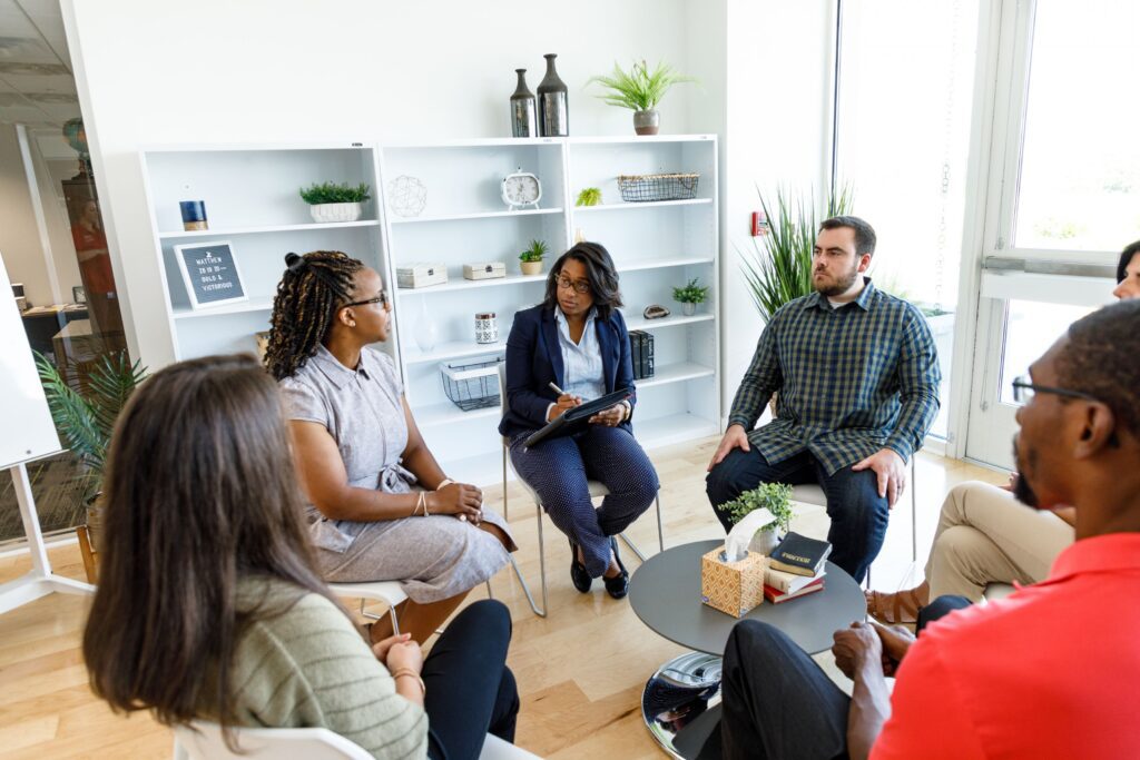 A Diverse Group Seated In A Circle, Engaged In Conversation &Amp; Idea Sharing