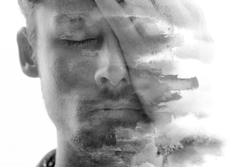 A Depressed Young Man Covering His Face With His Hand.